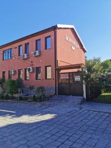 un gran edificio de ladrillo con un garaje delante de él en Guesthouse Zornitsa, en Hisarya