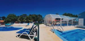 una piscina con sillas y una casa de cristal en Camping Villa Park Zambujeira do Mar, en Zambujeira do Mar