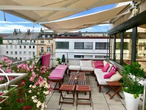 d'une terrasse avec des canapés et des tables sur un balcon. dans l'établissement Business Hotel Wiesbaden PRIME, à Wiesbaden