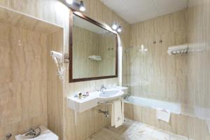 e bagno con lavandino, specchio e vasca. di Hotel Sao Joao De Deus by RIDAN Hotels a Elvas