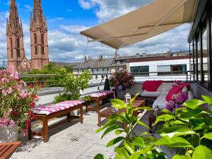 d'une terrasse avec des bancs et des tables sur un balcon avec une cathédrale. dans l'établissement Business Hotel Wiesbaden PRIME, à Wiesbaden