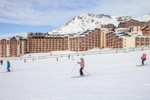 eine Gruppe von Personen, die im Schnee vor einem Hotel Ski fahren in der Unterkunft Résidence Les Temples du Soleil in Val Thorens