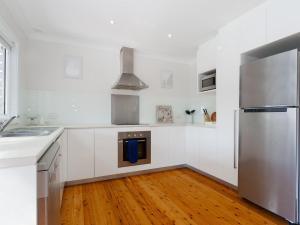 a kitchen with white cabinets and a stainless steel refrigerator at Rubys Retreat, 44 Achilles Street - pet friendly, aircon, wifi & boat parking in Shoal Bay