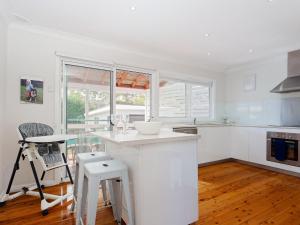 a white kitchen with a counter and a table at Rubys Retreat, 44 Achilles Street - pet friendly, aircon, wifi & boat parking in Shoal Bay