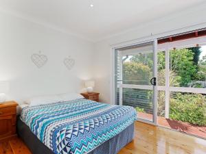 a bedroom with a bed and a large window at Rubys Retreat, 44 Achilles Street - pet friendly, aircon, wifi & boat parking in Shoal Bay