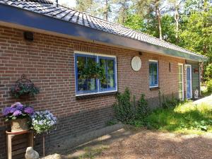 ein Backsteinhaus mit Fenstern und Blumen im Hof in der Unterkunft Holiday home bos en heide in Otterlo