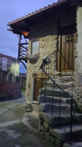 a stone building with a staircase leading to a door at A Paragűeria in Sas de Penelas