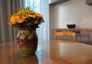 un jarrón lleno de flores amarillas sentadas en una mesa en Dizaina apartamenti Saules koks, en Sigulda