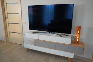 TV de pantalla plana en un centro de entretenimiento blanco en Dizaina apartamenti Saules koks, en Sigulda