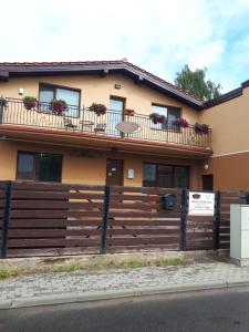 dom z płotem i kwiatami na balkonach w obiekcie Juro Guest House w Szawlach