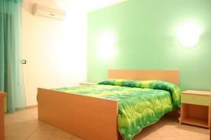 um quarto com uma cama com um edredão verde em L'Arcobaleno em Santa Maria la Palma