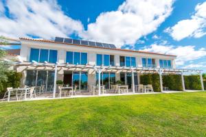 un edificio bianco con tavoli e sedie su un prato di Quinta Dos Perfumes a Tavira