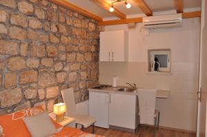 uma cozinha com uma parede de pedra e uma mesa e cadeiras em Apartments Lucic em Dubrovnik