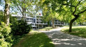 a building in the middle of a park with trees at FAVORITE Parkhotel in Mainz