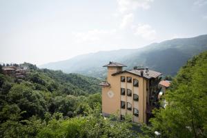 ein Gebäude auf einem Hügel mit Bergen im Hintergrund in der Unterkunft Hotel Resort & Spa Miramonti in Rota d'Imagna