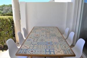 - une table sur un balcon avec des chaises blanches dans l'établissement Ground Floor with private garden Bellresguard, à Port de Pollença