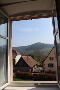 a window with a view of houses and mountains at Ancien Presbytère Albert Schweitzer in Gunsbach