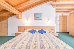 1 dormitorio con 1 cama grande con almohadas azules en Hotel Garni la Stua, en Selva di Cadore