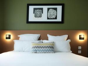 a bed with white pillows in a bedroom with green walls at Logis Hôtel de l'Europe in Poitiers