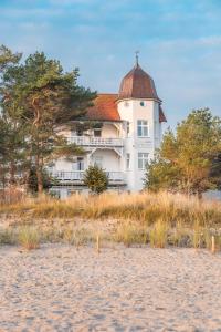 duży biały budynek z czerwonym dachem na plaży w obiekcie Strandhotel zur Promenade w mieście Binz