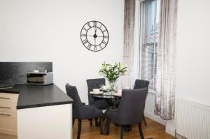 una cocina con mesa y sillas y un reloj en la pared en Parkhill Luxury Serviced Apartments - City Centre Apartments, en Aberdeen