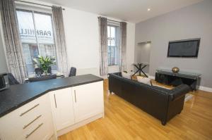 sala de estar con sofá negro y TV en Parkhill Luxury Serviced Apartments - City Centre Apartments, en Aberdeen