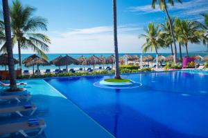 a large swimming pool with palm trees and umbrellas at Crown Paradise Club All Inclusive in Puerto Vallarta