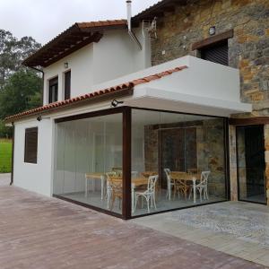 una extensión de una casa con puertas de cristal y una mesa en Posada las Albarcas, en La Cavada