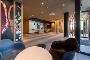 un hall avec une table et des chaises dans un bâtiment dans l'établissement ibis Regensburg Zentrum, à Ratisbonne