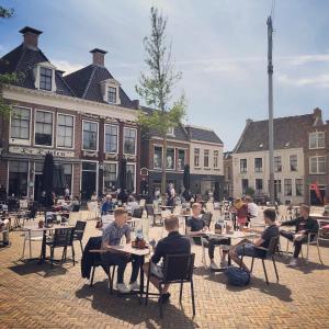 een groep mensen die aan een tafel op een binnenplaats zitten bij Hotel Grandcafe De Doelen in Franeker