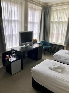 een hotelkamer met 2 bedden en een bureau met een televisie bij Hotel Grandcafe De Doelen in Franeker