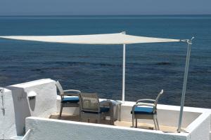 two chairs and a white umbrella on top of the ocean at Dar Corniche La Marsa (Adults Only) in La Marsa