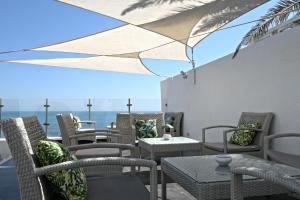 a patio with chairs and tables with the ocean in the background at Dar Corniche La Marsa (Adults Only) in La Marsa