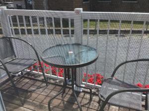 a table and chairs on a balcony with a fence at Petit Hôtel Amara in La Malbaie