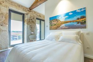 una camera da letto con un grande letto bianco e ampie finestre di GOLDNATURE a Gondomar