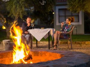 a man and a woman sitting around a fire at Kotroni Villas in Finikounta