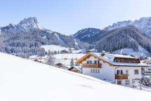 dom w śniegu z górami w tle w obiekcie Garni Charlotte w mieście Selva di Val Gardena