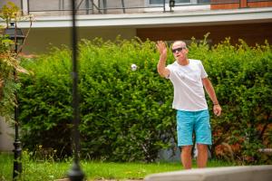 un hombre de pie en la hierba lanzando una pelota de béisbol en Hostel Le Hüb Grenoble, en Grenoble