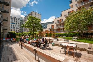 un grupo de personas sentadas en mesas en una terraza de madera en Hostel Le Hüb Grenoble, en Grenoble