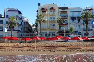 a row of red umbrellas on a beach with buildings at URH Sitges Playa in Sitges