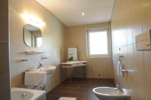 bagno con lavandino, servizi igienici e specchio di B&B Hotel Heidi a Dobbiaco