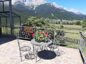 een tafel en stoelen op een balkon met bloemen bij Appartamento G.& G. in Dosoledo