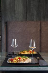 Duas pizzas numa mesa com dois copos de vinho. em Hotel Cool Zagreb Airport em Velika Gorica