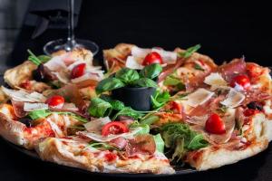 uma pizza sentada em cima de um prato preto em Hotel Cool Zagreb Airport em Velika Gorica