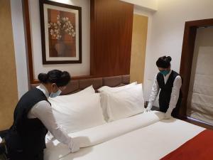 two women in a hotel room making a bed at Hotel MBC Citadel Nashik in Nashik