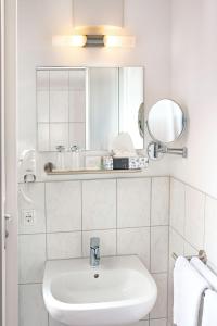 a white bathroom with a sink and a mirror at centra Hotel in Schwedt