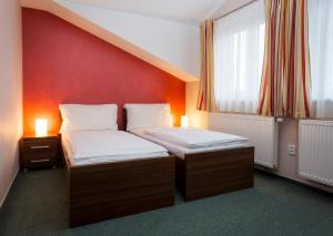 two beds in a room with a red wall at Pension Bed&Breakfast in Kutná Hora