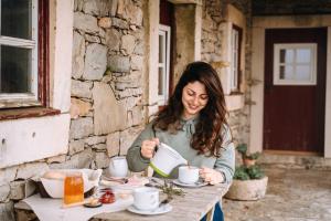 una mujer sentada en una mesa con una taza de café en Casas de Pedra - Quinta da Escola, en Alvados