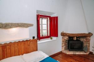 1 dormitorio con chimenea y ventana roja en Casas de Pedra - Quinta da Escola, en Alvados