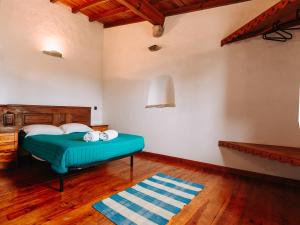 1 dormitorio con cama verde y suelo de madera en Casas de Pedra - Quinta da Escola, en Alvados